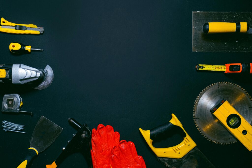 Flat lay of various construction tools on black background, perfect for ads with copy space.